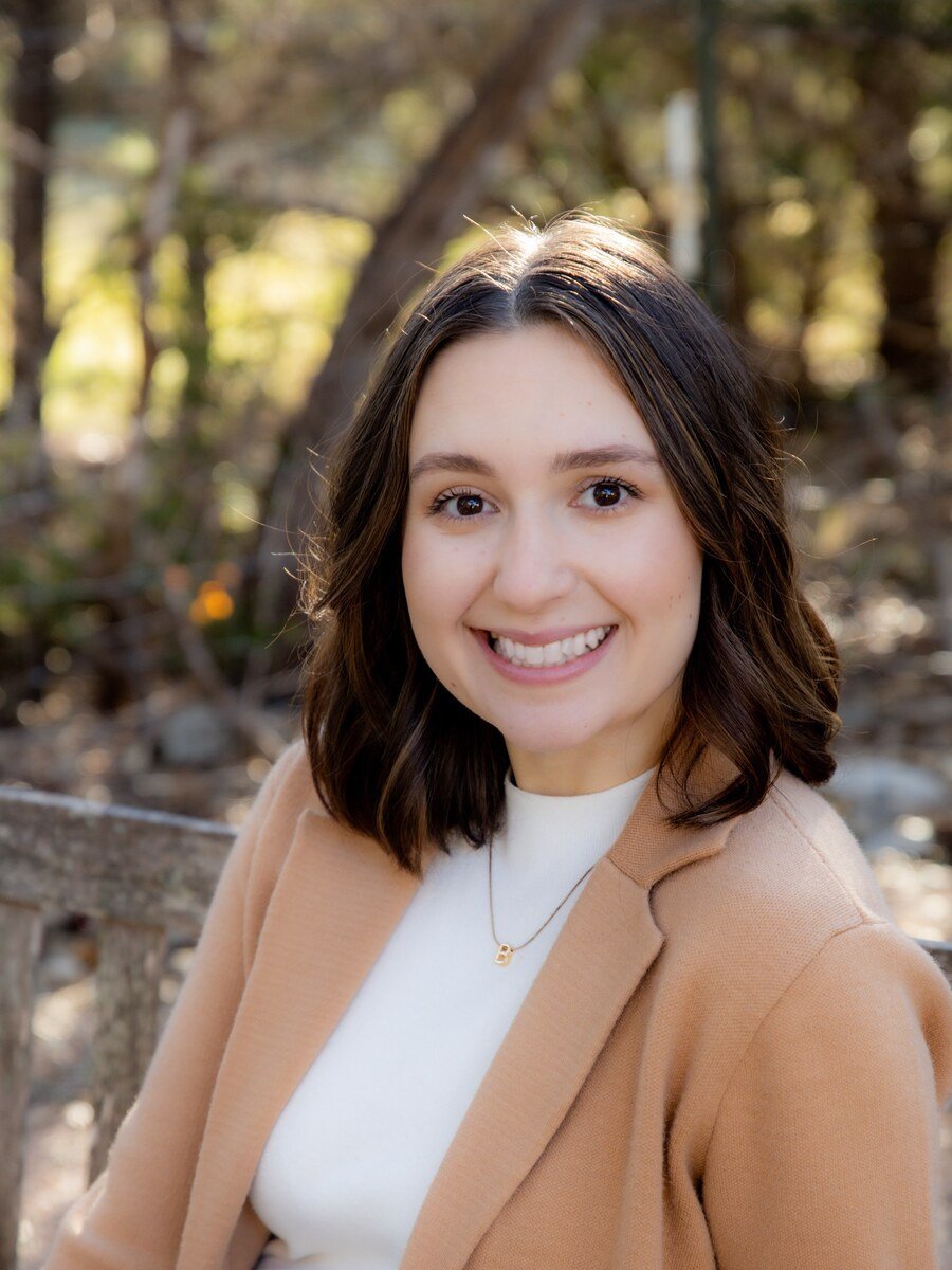 Portrait of Danielle Clark smiling in a tan blazer over a white top outdoors
